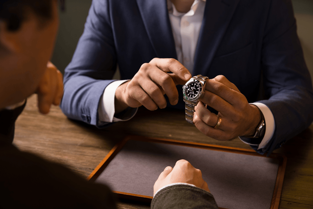 Luxury watch dealer showing a Rolex GMT-Master II stainless steel sports watch to a client during a consultation at Bob’s Watches.